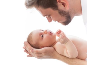 Father and baby. Close-up of father holding cute little baby in hands and smiling